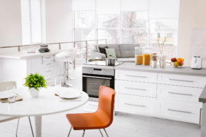 Modern kitchen interior of studio apartment with large counter and white round table © belchonock/DepositPhotos